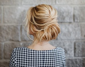 Blonde woman in a houndstooth dress with a French twist hairstyle